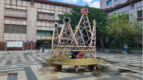 &nbsp;迷宮，設置於車站東北角戶外廣場之作品，創作者為陳姿女藝術家，將廣場的地坪鋪面排成視覺性的迷宮，位於中心位置設下皇冠造型的寶座作為迷宮遊戲的終點，周圍則設置40公分立方的凳子彷彿侍衛分立四周。28個環繞迷宮四周的凳子，實際上是一盞盞華麗的燈。
&nbsp;