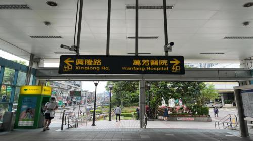 萬芳醫院站位於興隆路旁，於1996年3月通車啟用，站體與醫院共構，為首例與醫院共構之捷運車站。站體為高架四層之車站，設有1座出入口，三樓為大廳及月台層，四樓為天橋層，以轉換乘車方向，設有側式月台兩座。【圖/地面層出口，往左興隆路三段、往右萬芳醫院】
&nbsp;